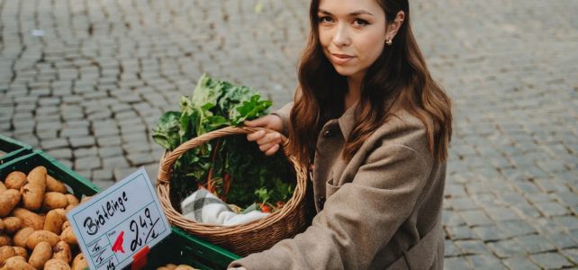Jak wprowadzić zdrowe nawyki do codziennego życia Young woman shopping at Erfurt farmers market, holding basket with fresh vegetables. Capturing local shopping culture.